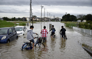 FRA03 KOSHIGAYA (JAPÓN) 10/9/2015 Niños circulan con sus bicicletas por una calle inundada en Koshih¡gaya, en el barrio de Saitama en Tokio, hoy 10 de septiembre de 2015. El tifón Etau causó hoy lluvias récord, graves inundaciones y la evacuación de casi 100.000 personas en el centro y el este de Japón, donde el fenómeno meteorológico también ha dejado al menos un desaparecido y decenas de heridos.EFE/FRANCK ROBICHON