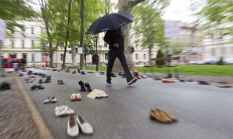 BAT01 ZAGREB (CROACIA) 28/04/2016.- Un viandante pasa junto a decenas de pares de zapatos usados que fueron colocados hoy en la céntrica plaza Zrinjevac de Zagreb durante una protesta convocada por un importante sindicato contra el desempleo y la emigración masiva de jóvenes del país balcánico, en Zagreb, Croacia, hoy, 28 de abril de 2016. Esta "protesta de zapatos", que pretende simbolizar a los que se han visto obligados a abandonar Croacia en busca de trabajo en otros países, fue organizada por la Unión de los Sindicatos Independientes de Croacia (SSSH) ante el próximo Día del Trabajo el 1 de mayo. EFE/Antonio Bat