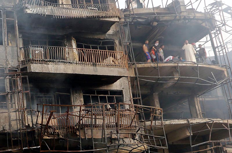 EBAG16. Baghdad (Iraq), 03/07/2016.- Iraqis look on as they inspect the site of suicide car bomb attack in the Karada district of central Baghdad, Iraq, 03 July 2016. At least 23 people were killed and 70 others were wounded in a suicide car bomb attack targeted Karada district of Baghdad and other attack by a roadside bomb in Shaab market , Iraqi police said. (Atentado, Bagdad) EFE/EPA/ALI ABBAS