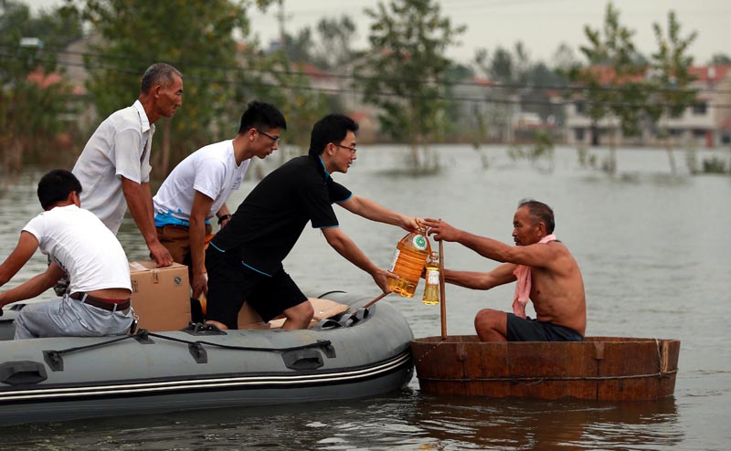 TWT06. Wuhan (China), 18/07/2016.- A picture made available on 23 July 2016 of volunteers giving food supplies to a villager in a makeshift boat on flood water, Xinhua Village of Xinchang county in Wuhan city, Hubei Province of central China on 18 July 2016. Floods caused by heavy rainfall in north and central have killed more than 70 people, leaving many missing and hundreds of thousands homeless according to local reports. (Inundaciones) EFE/EPA/MARK CHINA OUT