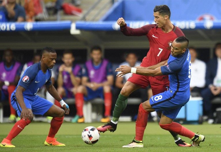 France's defender Patrice Evra (L) and France's forward Dimitri Payet vie with Portugal's forward Cristiano Ronaldo during the Euro 2016 final football match between Portugal and France at the Stade de France in Saint-Denis, north of Paris, on July 10, 2016. / AFP PHOTO / PHILIPPE DESMAZES