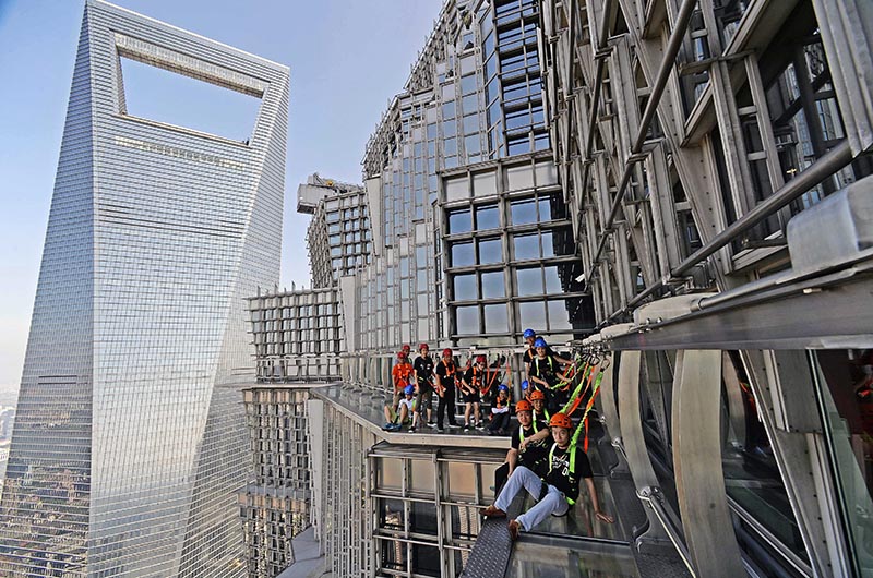 CH01. SHANGHÁI (CHINA), 28/07/2016.- Fotografía disponible hoy, viernes 29 de julio de 2016, de personas caminando sobre una pasarela acristalada en el piso 88 de la Torre Jinmao en Shanghái (China). La pasarela está abierta a los turistas, quienes pueden caminar ayudados de cuerdas de seguridad. EFE/XI LI/PROHIBIDO SU USO EN CHINA