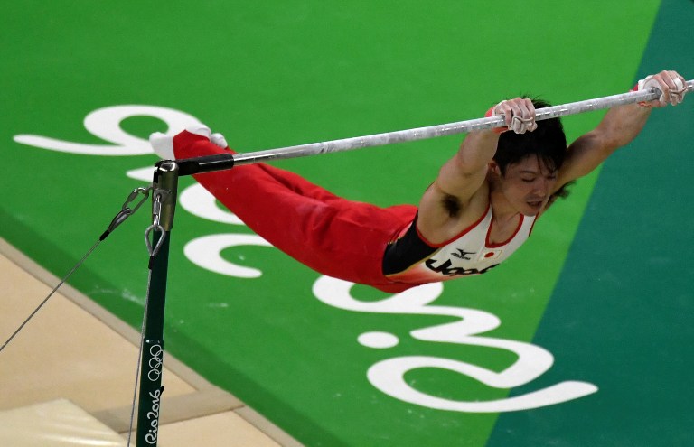 An overview shows Japan's Kohei Uchimura competing in the horizontal bar of the men's team final of the Artistic Gymnastics at the Olympic Arena during the Rio 2016 Olympic Games in Rio de Janeiro on August 8, 2016. / AFP PHOTO / Antonin THUILLIER