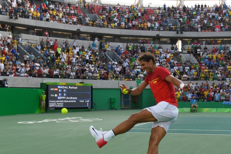 Spain's Rafael Nadal kicks a signed tennis ball into the crowd after winning his men's second round singles tennis match against Italy's Andreas Seppi at the Olympic Tennis Centre of the Rio 2016 Olympic Games in Rio de Janeiro on August 9, 2016. / AFP PHOTO / Luis Acosta