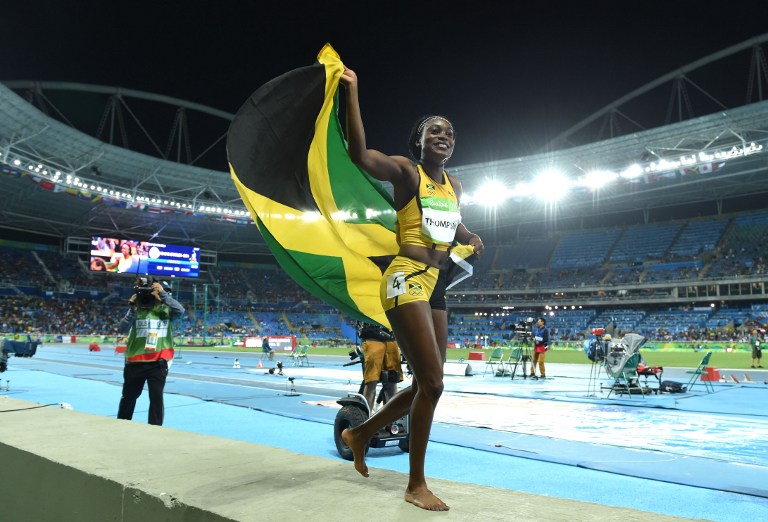 Jamaica's Elaine Thompson holds up a flag as she celebrates after winning the Women's 100m Final during the athletics event at the Rio 2016 Olympic Games at the Olympic Stadium in Rio de Janeiro on August 13, 2016.   / AFP PHOTO / Toshifumi KITAMURA