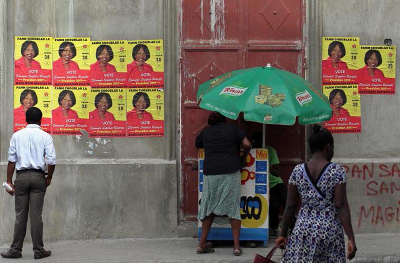 HAI08 PUERTO PRÍNCIPE (HAITÍ) 18/11/16.- Un hombre observa los carteles de una de las candidatas, hoy viernes 18 de noviembre de 2016, en la ciudad de Puerto Príncipe. El Gobierno de Haití anunció hoy el cierre de su frontera mañana y el domingo por la celebración este último día de las elecciones generales, medida que según el Ministerio del Interior haitiana asegura más control durante la jornada electoral. EFE/Alejandro Ernesto