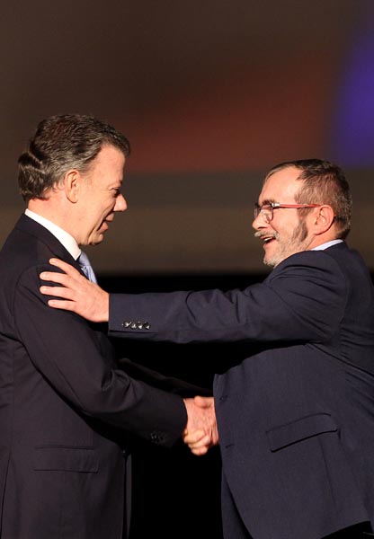 BOG108. BOGOTÁ (COLOMBIA), 24/11/2016.- El presidente de Colombia Juan Manuel Santos (i) y el jefe máximo de las FARC Rodrigo Londoño Echeverry (d) se felicitan luego de firmar el nuevo acuerdo de paz para terminar 52 años de conflicto armado interno hoy, jueves 24 de noviembre de 2016, en Bogotá (Colombia). Santos y "Timochenko" firmaron el acuerdo, que complementa el original del pasado 26 de septiembre en Cartagena de Indias, a las 11.30 hora local (16.30 GMT) en el Teatro Colón de Bogotá. Primero lo hizo el jefe guerrillero y luego el jefe de Estado, quienes utilizaron, al igual que en el primer acuerdo, un "balígrafo", bolígrafo fabricado con un casquillo de bala de fusil, que simboliza el tránsito de Colombia de la guerra a la paz. EFE/MAURICIO DUENAS CASTAÑEDA