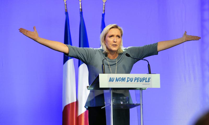TOPSHOT - French far-right Front National (FN) party's President, Marine Le Pen, gestures as she delivers a speech on stage during the FN's summer congress in Frejus, southern France, on September 18, 2016.  Marine Le Pen's slogan reading "In the name of the [French] people" is seen on the rostrum. / AFP / Franck PENNANT        (Photo credit should read FRANCK PENNANT/AFP/Getty Images)