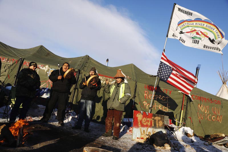 Activists (L-R) Eugene Sanchez of the Shoshone tribe, Jason Umtuch of the Yakima tribe, Martan Mendenhall of the Blackfeet tribe, and Hugh Ahnatock of the Inupiaq tribe sing as the sun rises inside of the Oceti Sakowin camp as demonstrations continue against plans to pass the Dakota Access pipeline near the Standing Rock Indian Reservation, near Cannon Ball, North Dakota, U.S., December 4, 2016.  REUTERS/Lucas Jackson